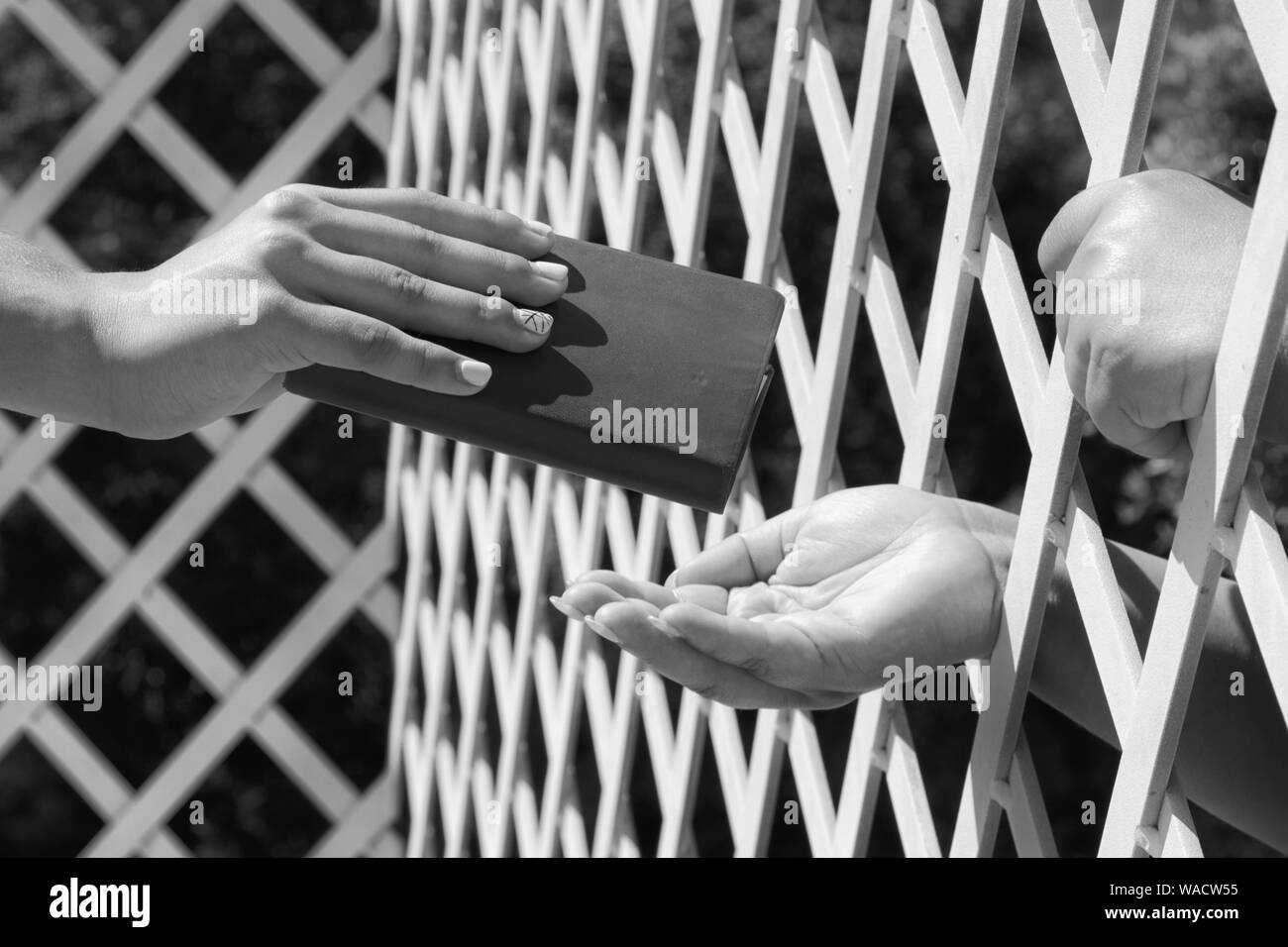 Hand on bars. Exchange of things trought bars. Social problems. Prision issue. Stock Photo
