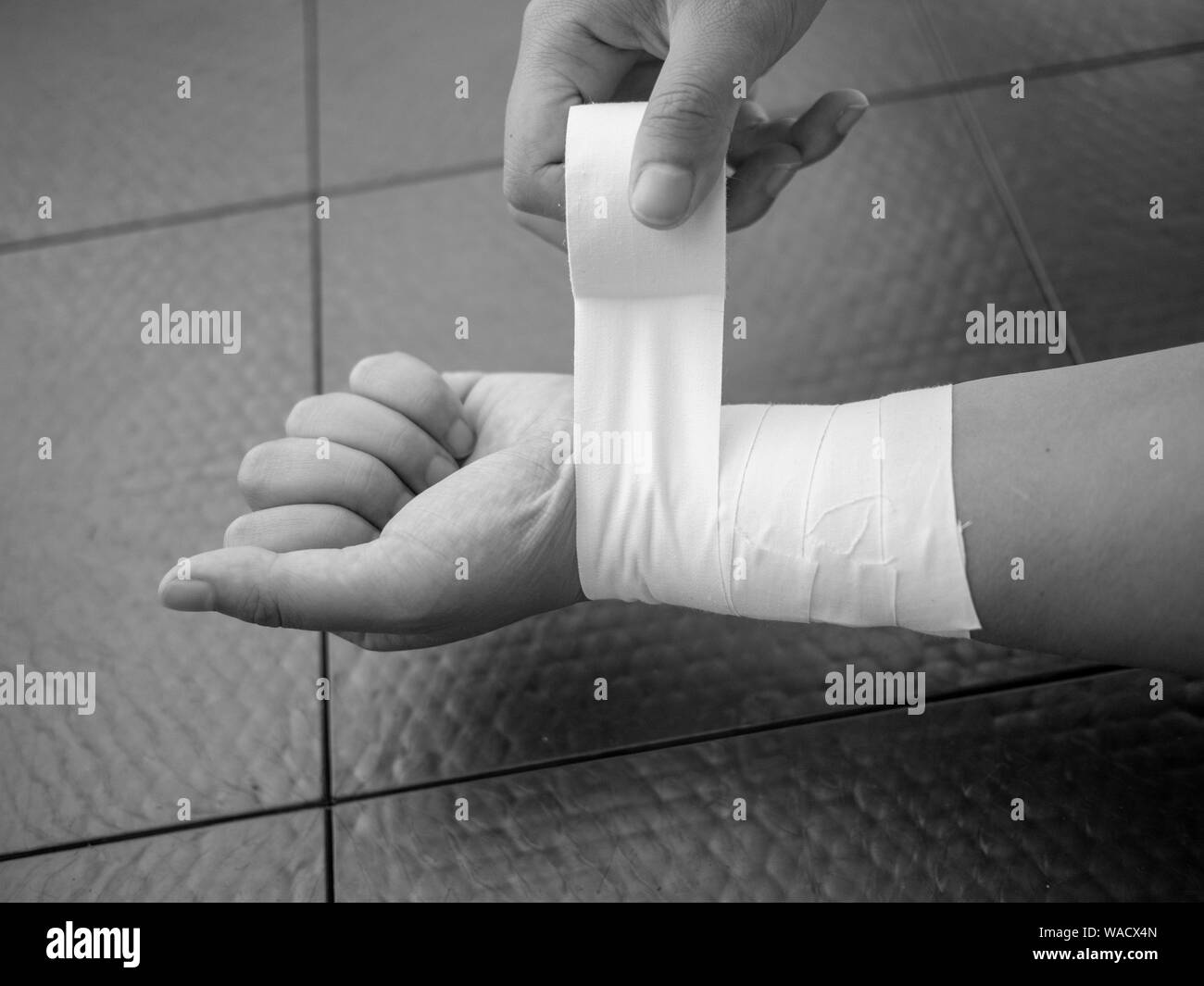 Black and white version of Athlete taping her wrist for injury and