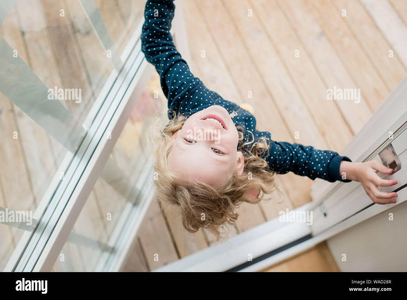 girl standing in the doorway at home laughing looking upside down Stock Photo