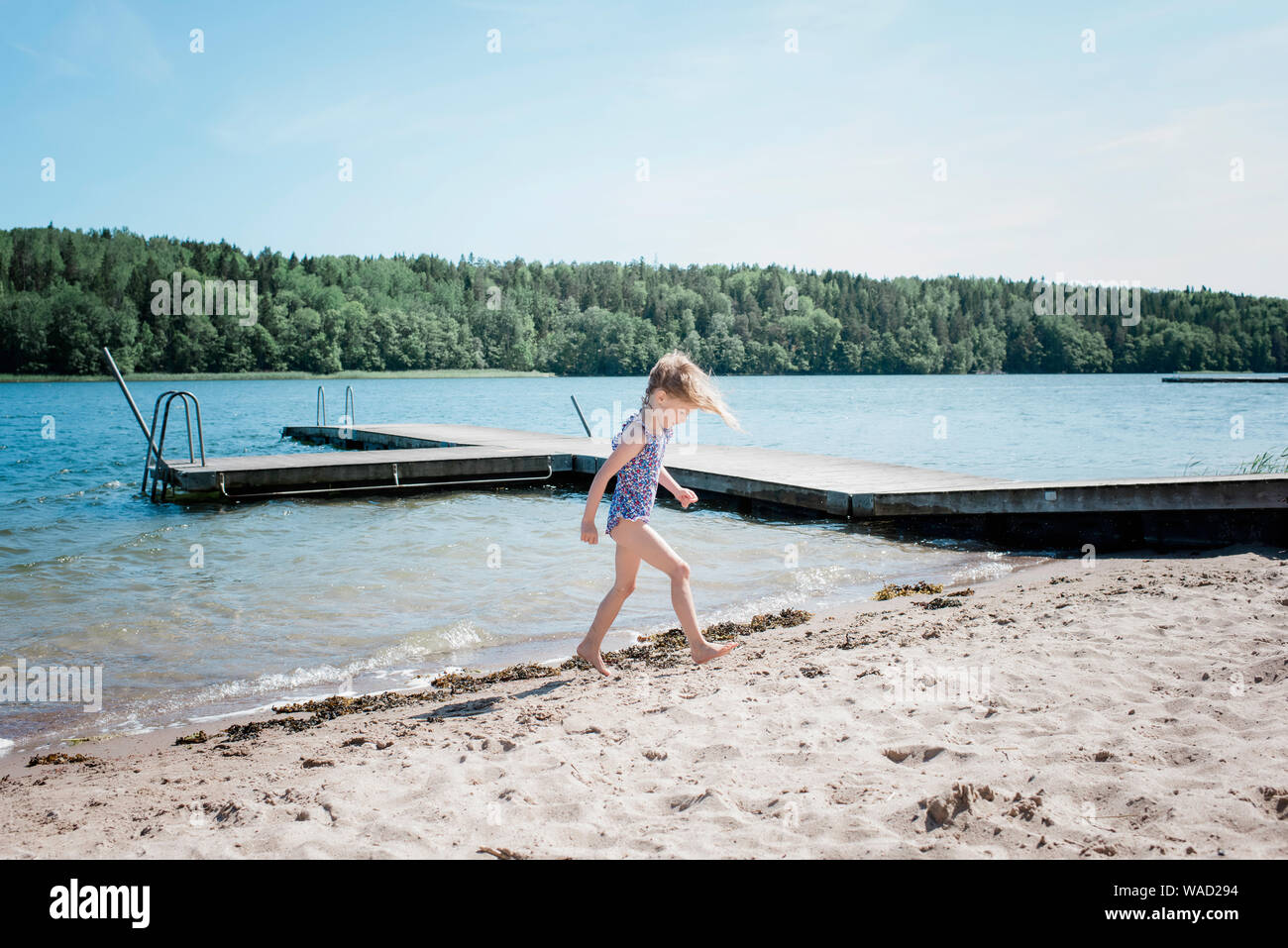 young blonde girl walking out of the sea to the beach in summer Stock Photo