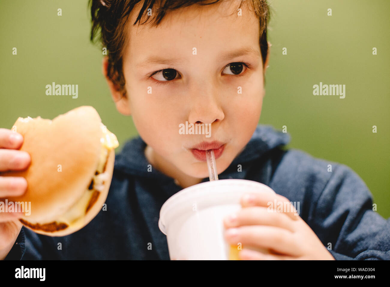Boy eating and drinking against green background Stock Photo