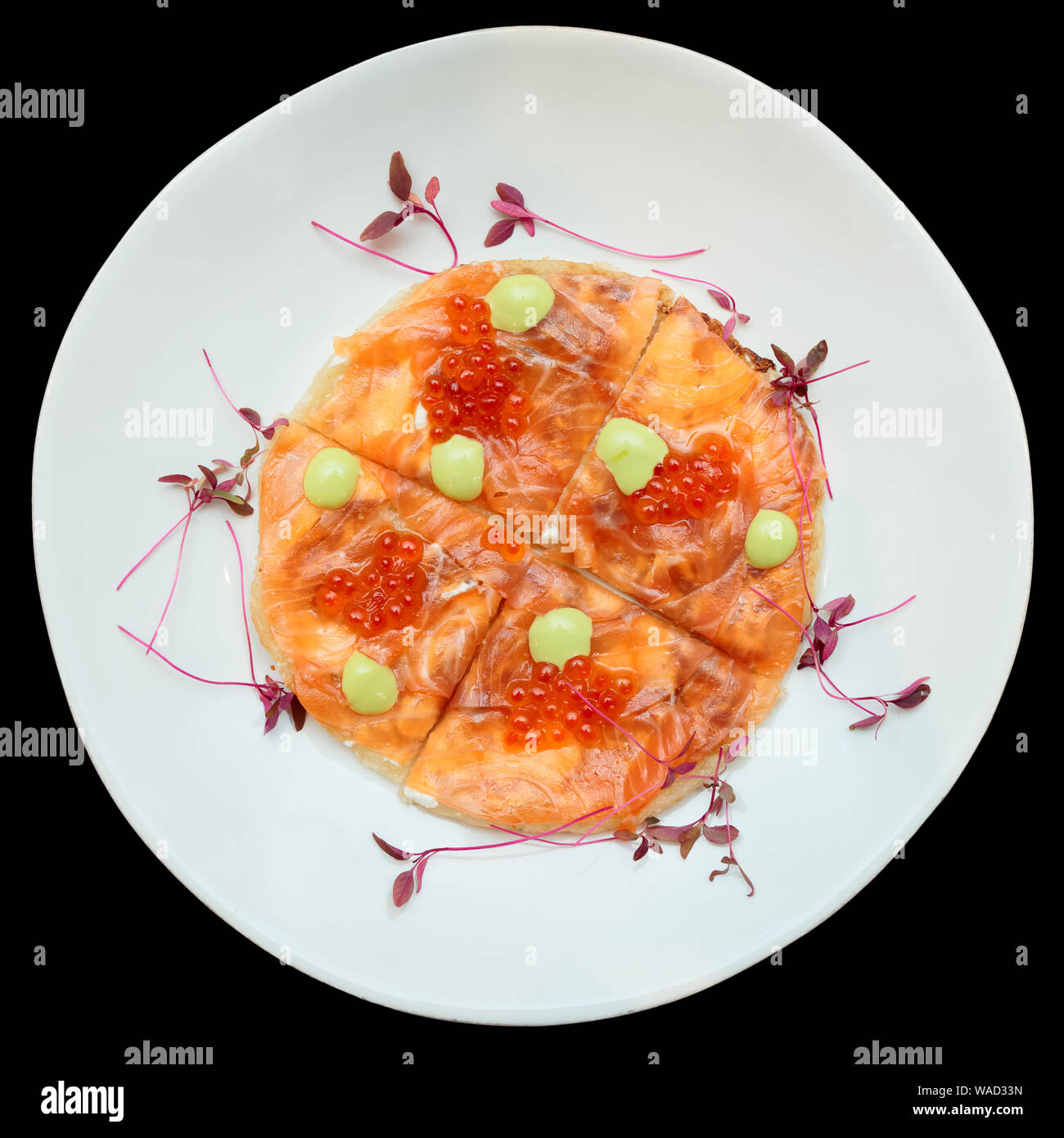 Salmon fillet and roe on Indian roti bread, uneven plate, isolated on black Stock Photo