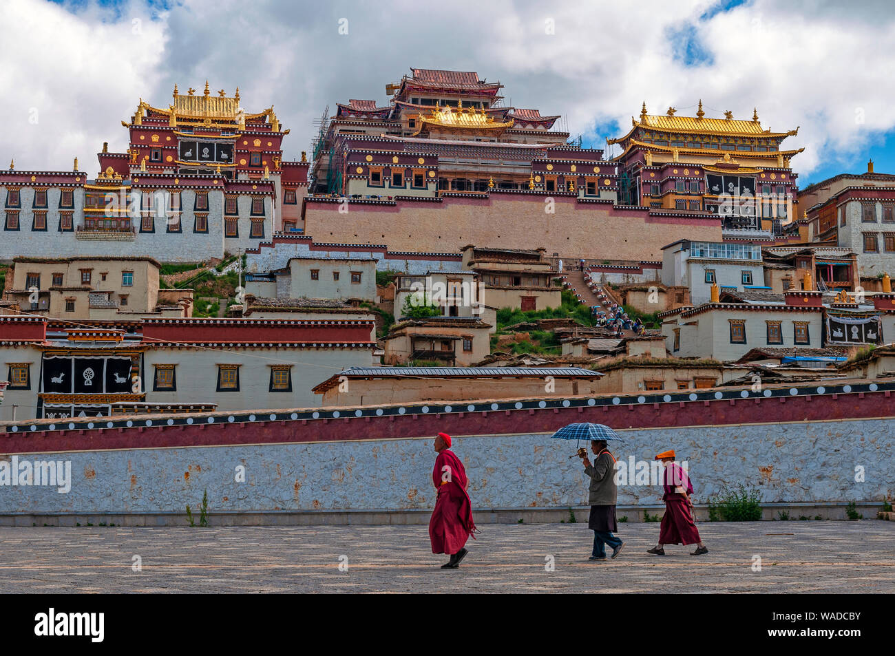 Tibetan monks walking in front of the Songzanlin monastery, also known as Ganden Sumtseling Gompa in Zhongdian, Shangri La, Yunnan province, China. Stock Photo