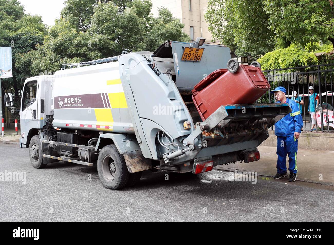 Chinese workers put bins of household food waste into a garbage truck