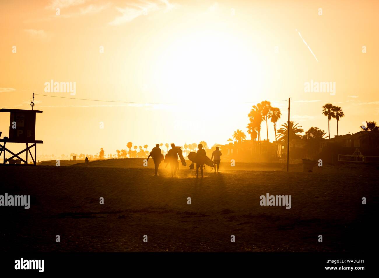 a group of bodyboarders and surfers leaving the beach at sunset Stock Photo