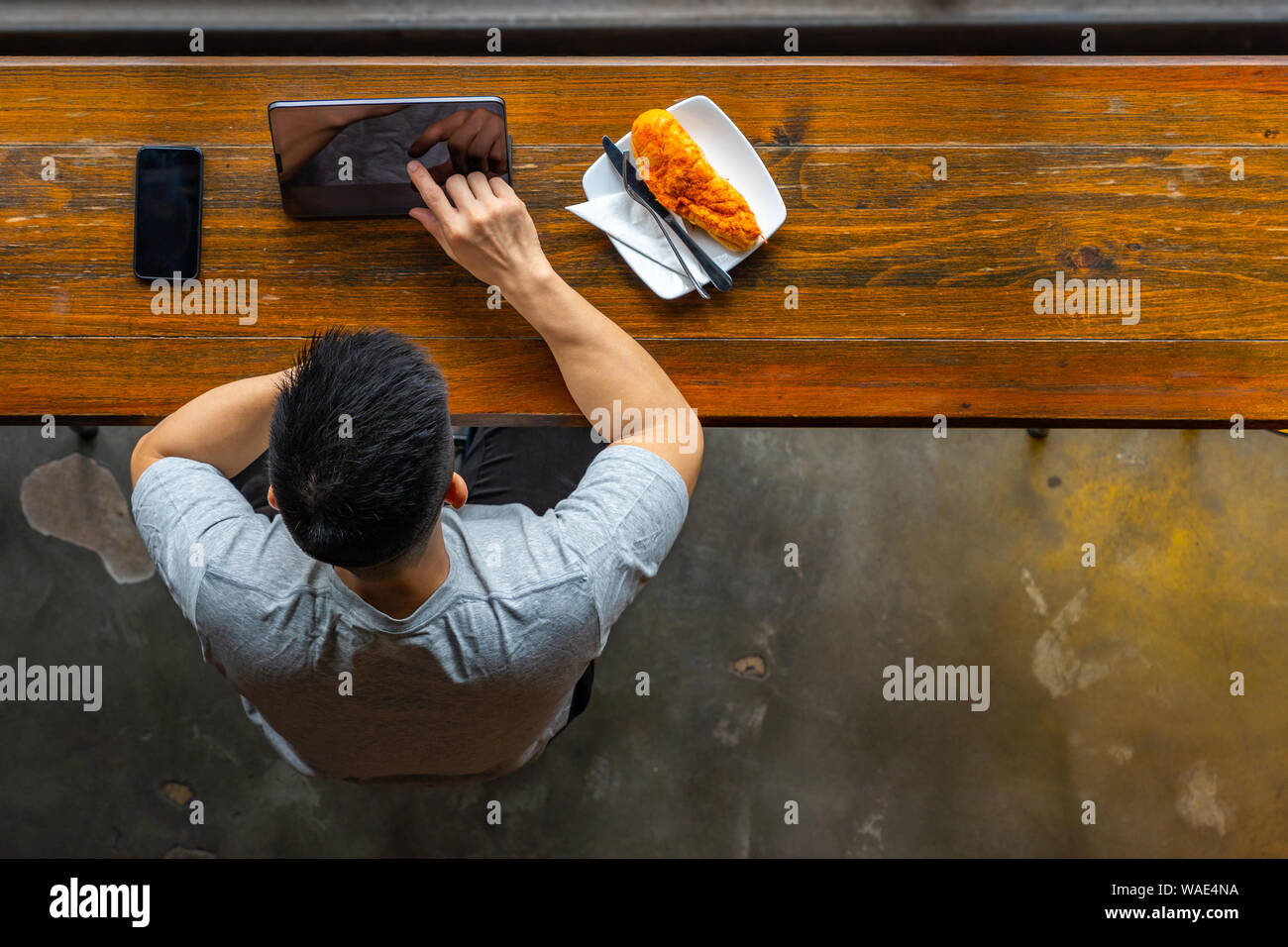 Top view of Asian millennial using tablet while having breakfast Stock Photo