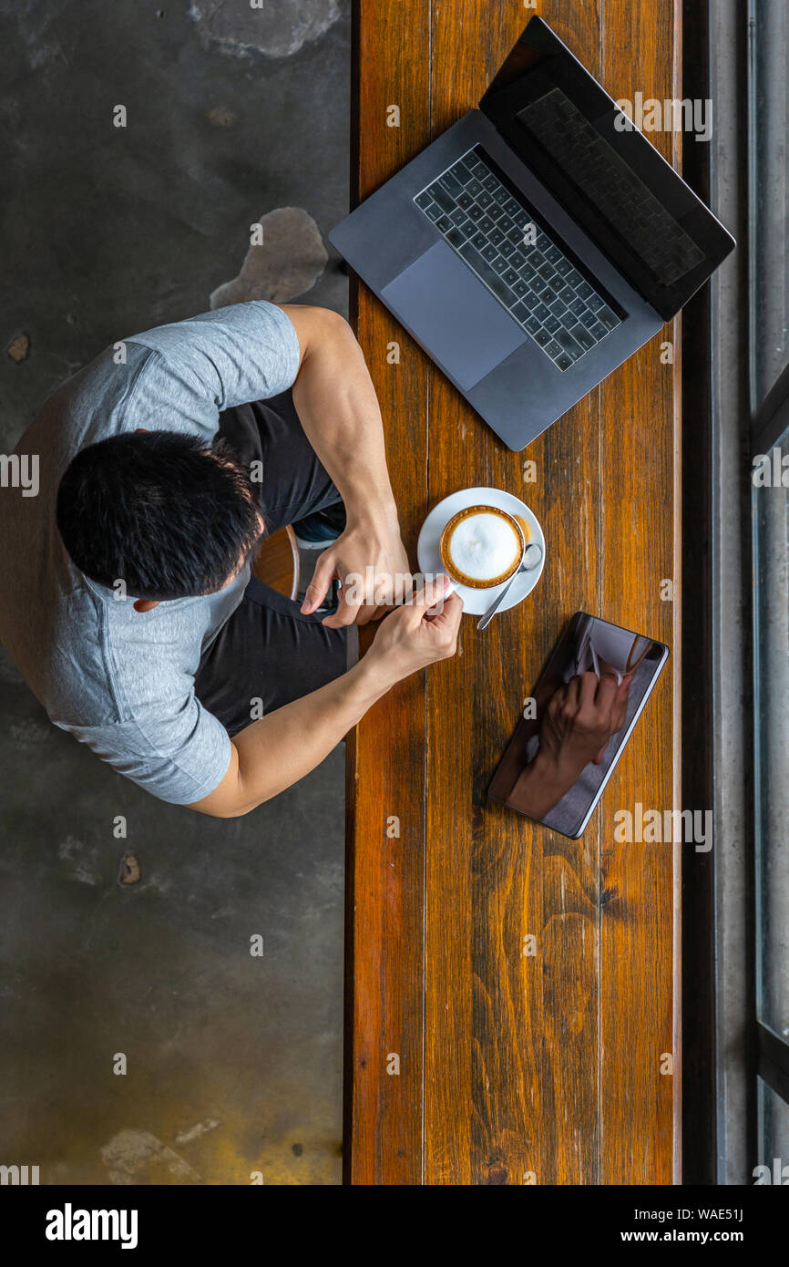 Vertical photo of muscled freelancer using laptop and drinking coffee Stock Photo