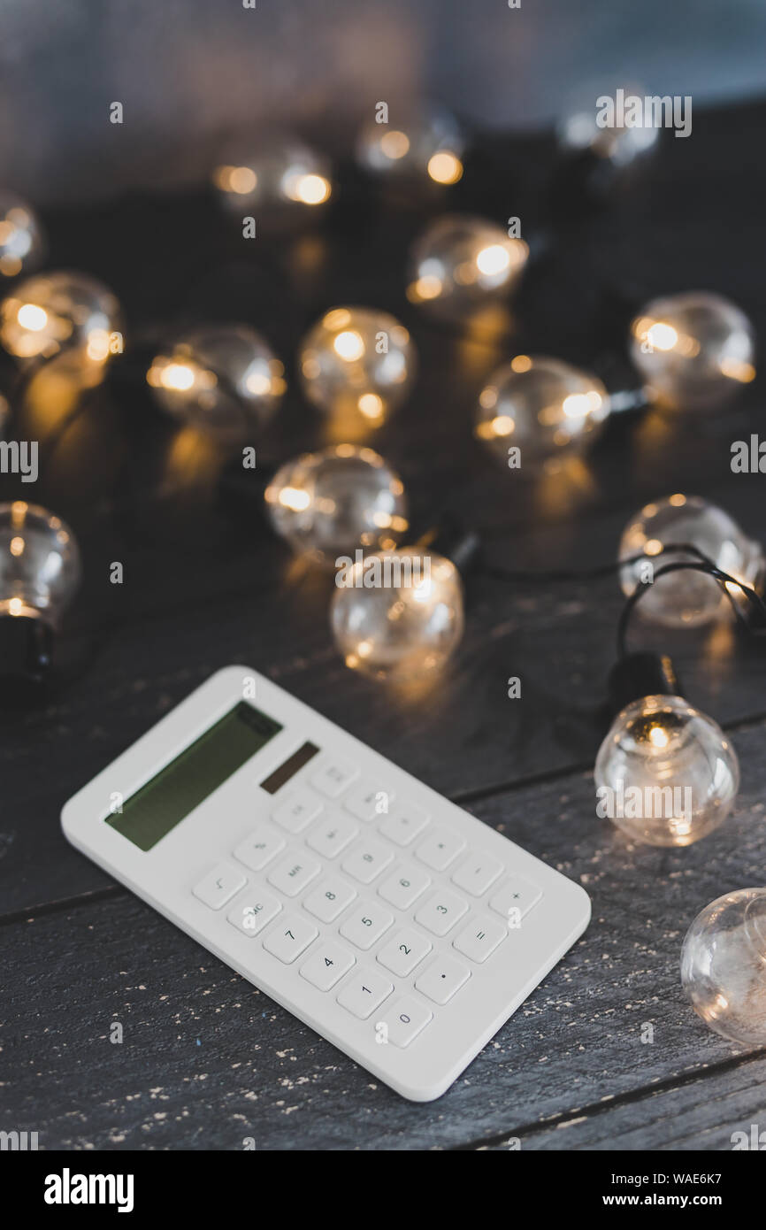 calculator on wooden desk surrounded by lightbulb string lights ...