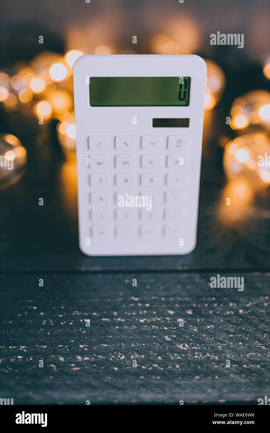 calculator on wooden desk surrounded by lightbulb string lights ...