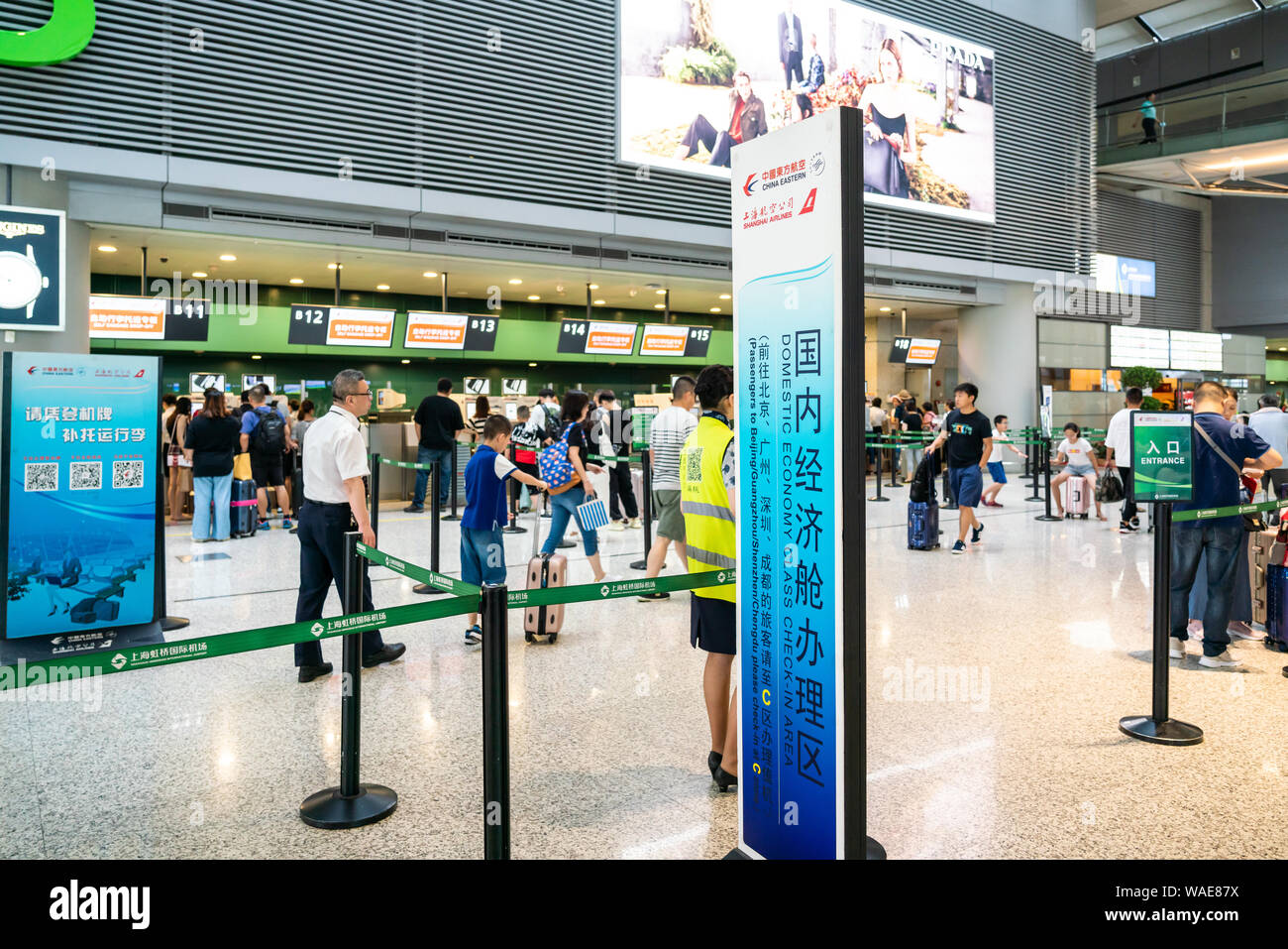 A view of the Domestic economy class check-in area of China Eastern Airlines in Terminal 2, Shanghai Hongqiao International Airport with passengers walking by. Stock Photo