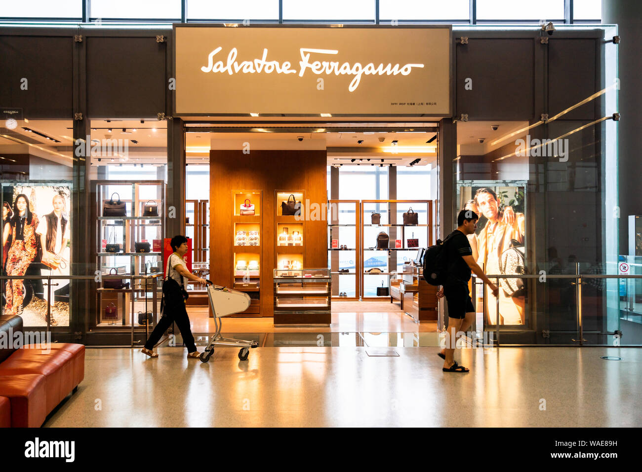 Pedestrians walk past an Italian luxury goods high-end retailer Salvatore Ferragamo store in Shanghai Hongqiao International Airport. Stock Photo