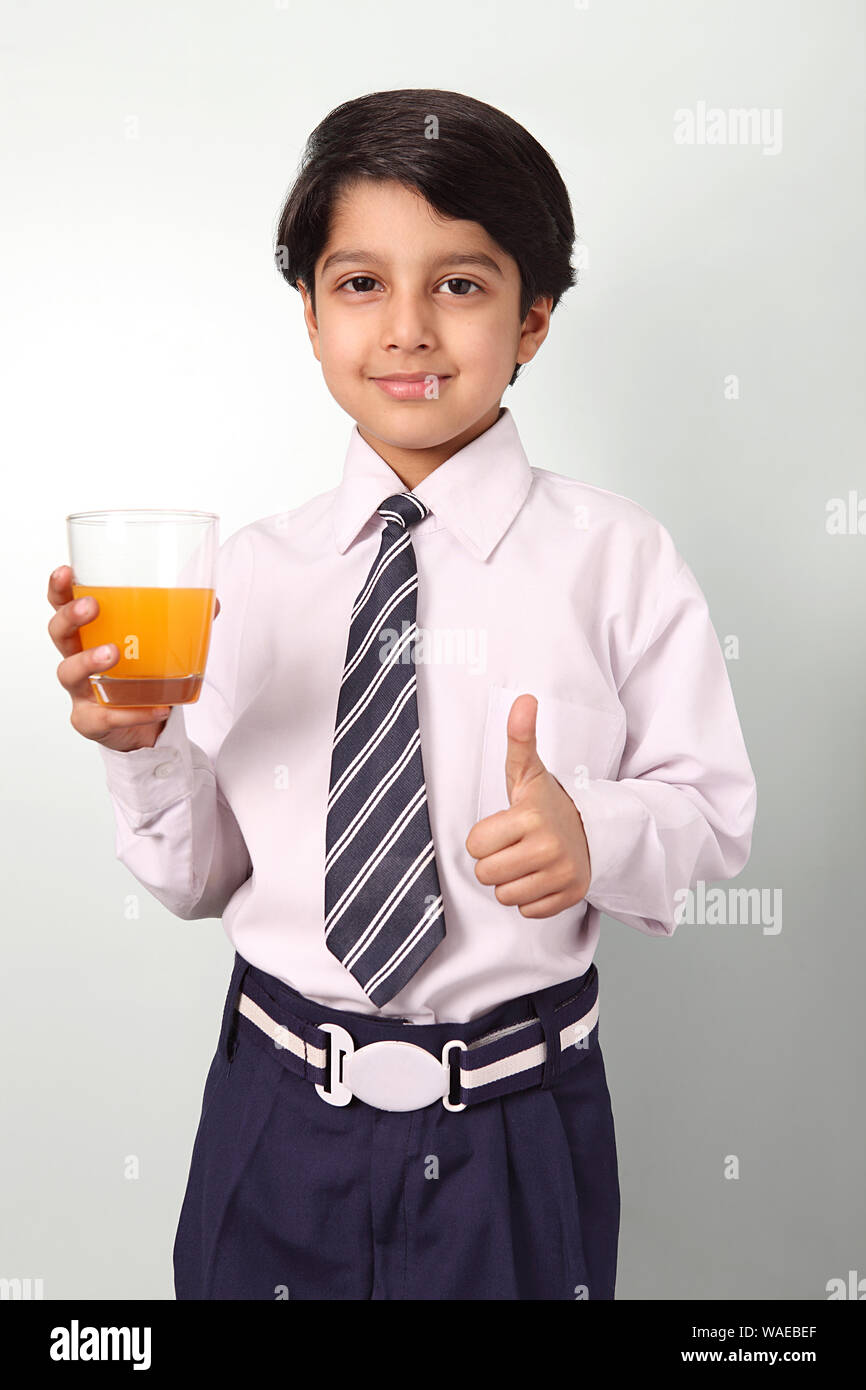 Schoolboy holding a glass of juice and showing thumbs up sign Stock Photo