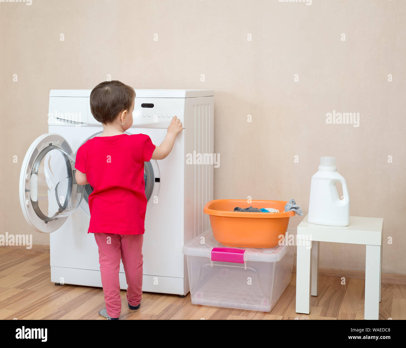 Little girl and washing machine in the background Stock Photo