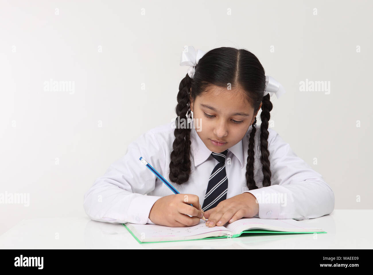 Schoolgirl writing in a notepad Stock Photo - Alamy
