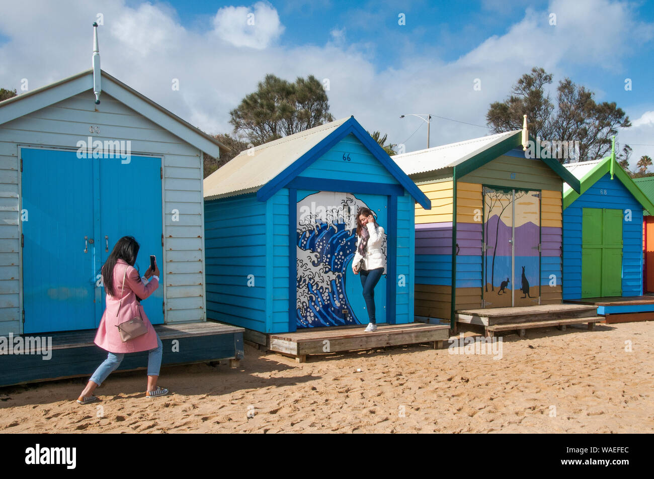 Female Asian tourists snapping selfies at the bathing boxes on Dendy Street Beach, Brighton, Port Phillip Bay, Melbourne Stock Photo