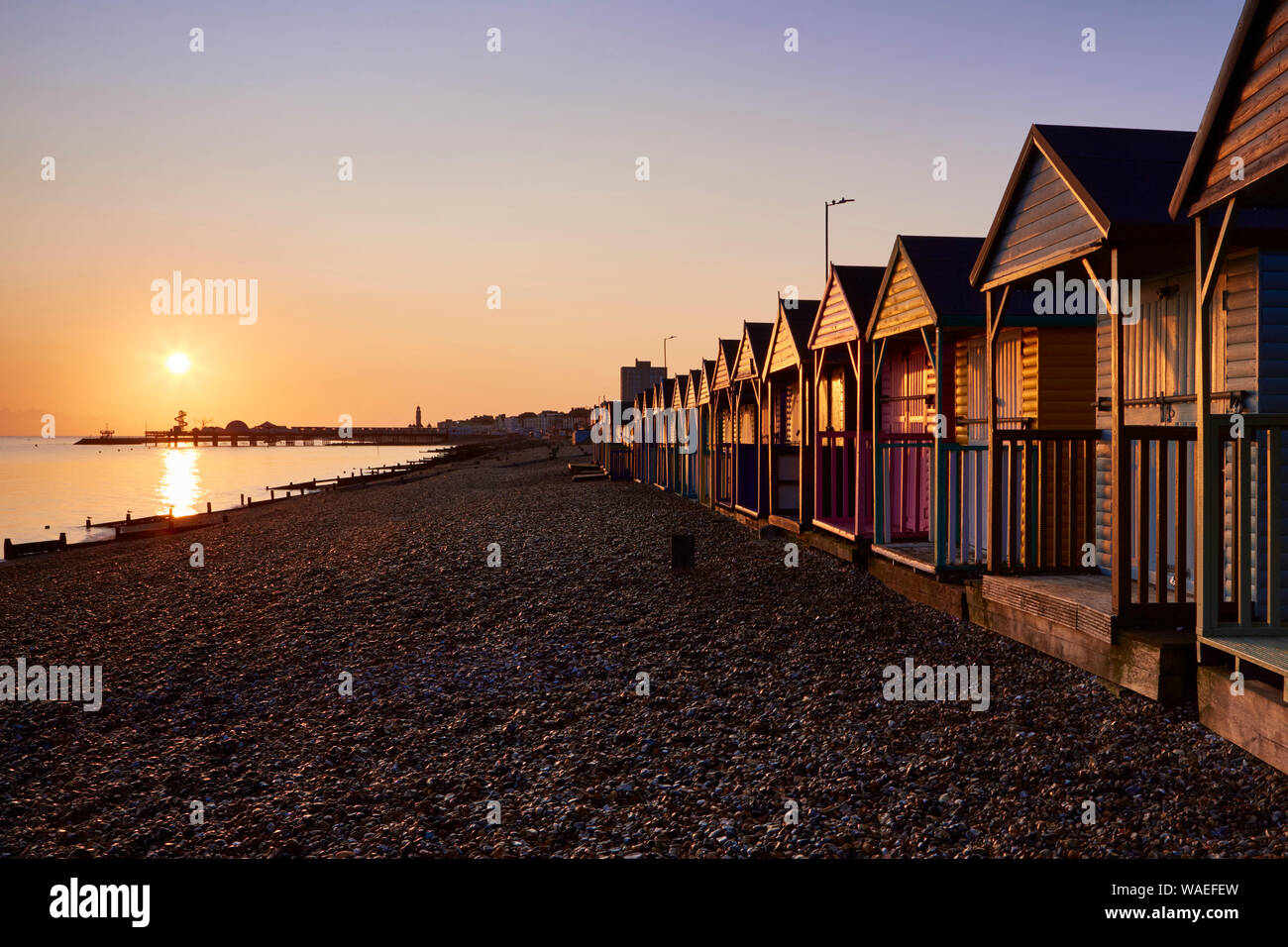 Herne Bay, Kent, UK. 20th August 2019: UK weather. Sunrise into clear skies over the pier at Herne bay lights up beach huts. The forecast is for hot sunny weather for the next few days and the bank holiday weekend which could cause some thunderstorms. Credit: Alan Payton/Alamy Live News Stock Photo