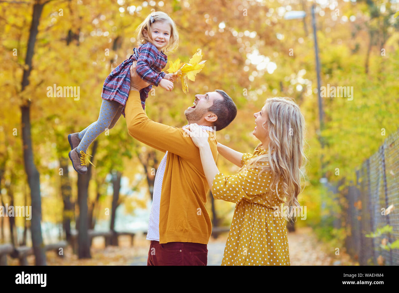 Laughing parents with charming girl in autumn Stock Photo