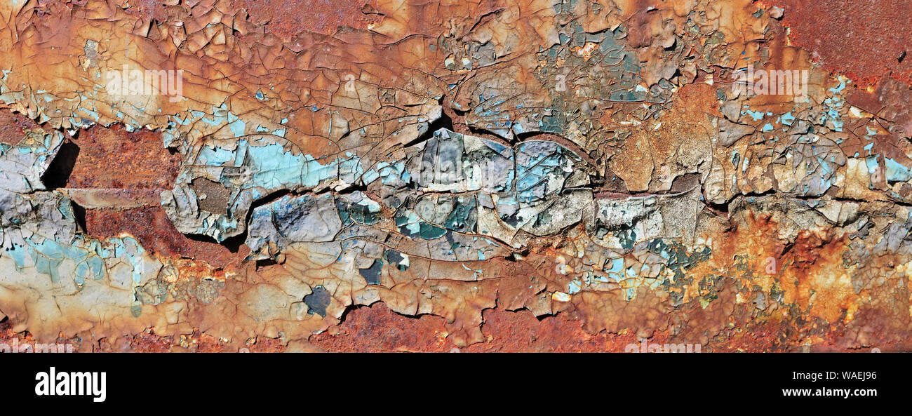 Enamelled  cracked  surface of the door hood of the old truck car was painted in yellow blue and red colors. Vintage texture panoramic concept Stock Photo