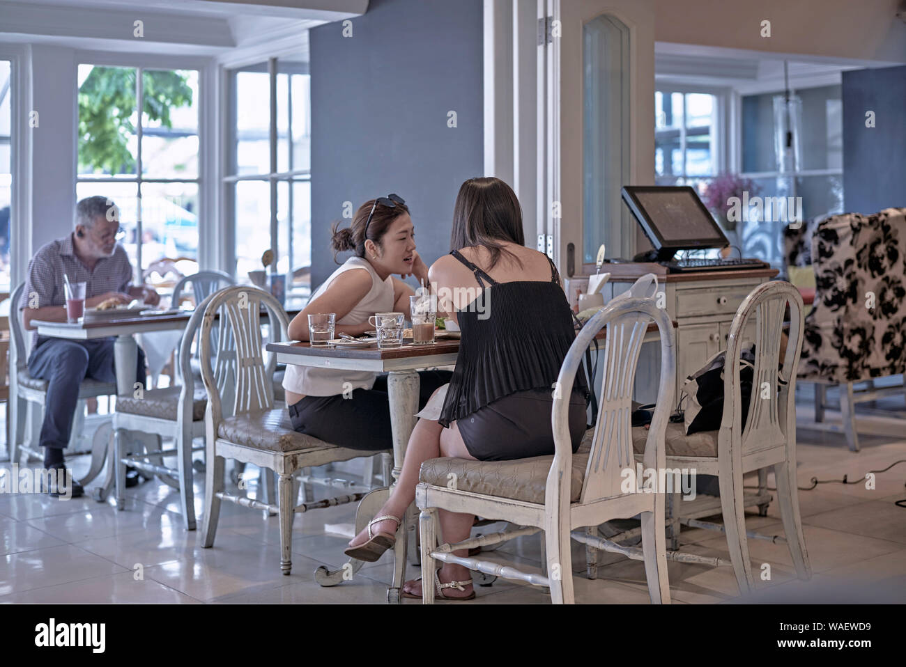 Two Women talking and passing the time of day chatting in a restaurant. Thailand Southeast Asia Stock Photo