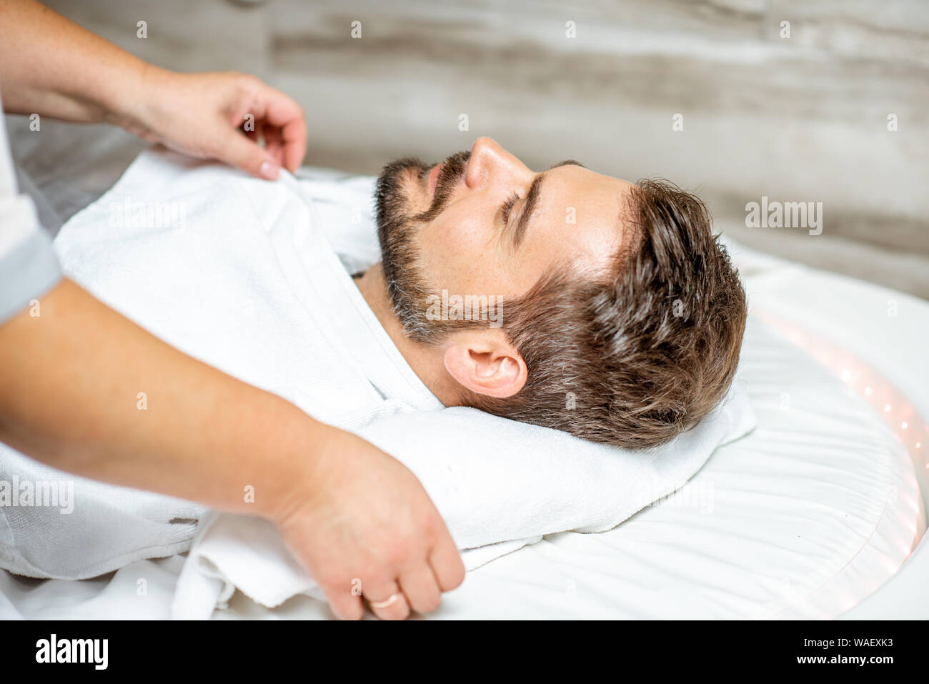 Man during a mud wrapping with special black mud, lying in the spa