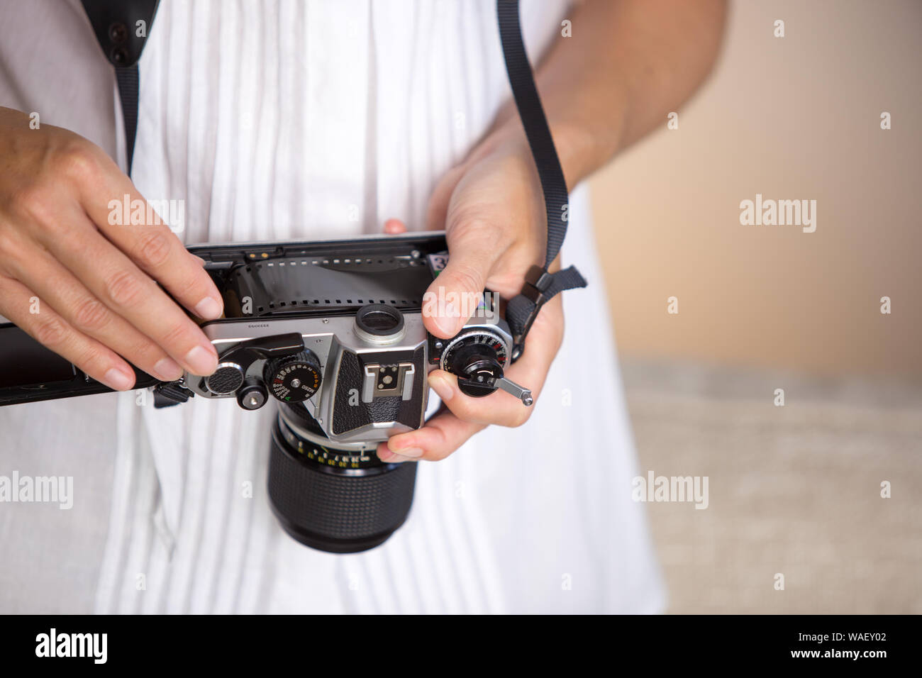 Contrast between old and modern times: a young woman fiddles with her vintage camera hanging from her neck Stock Photo