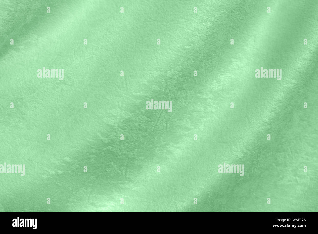 Trendy mint colored Background of soft draped fabric. Beautiful velvet textured cloth for making clothes and curtains. Textile background texture. Stock Photo