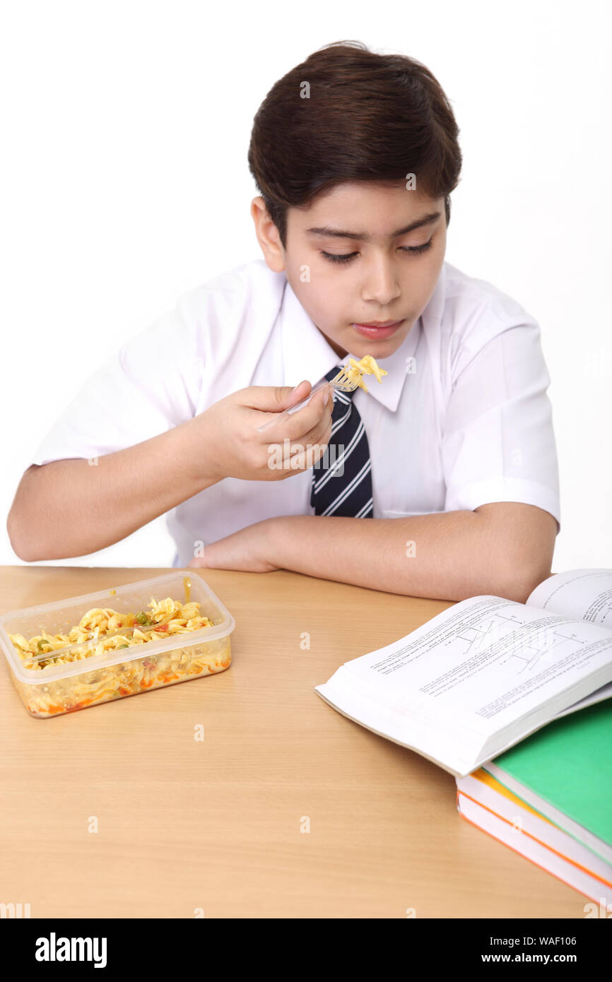 Schoolboy eating lunch in classroom and studying Stock Photo - Alamy