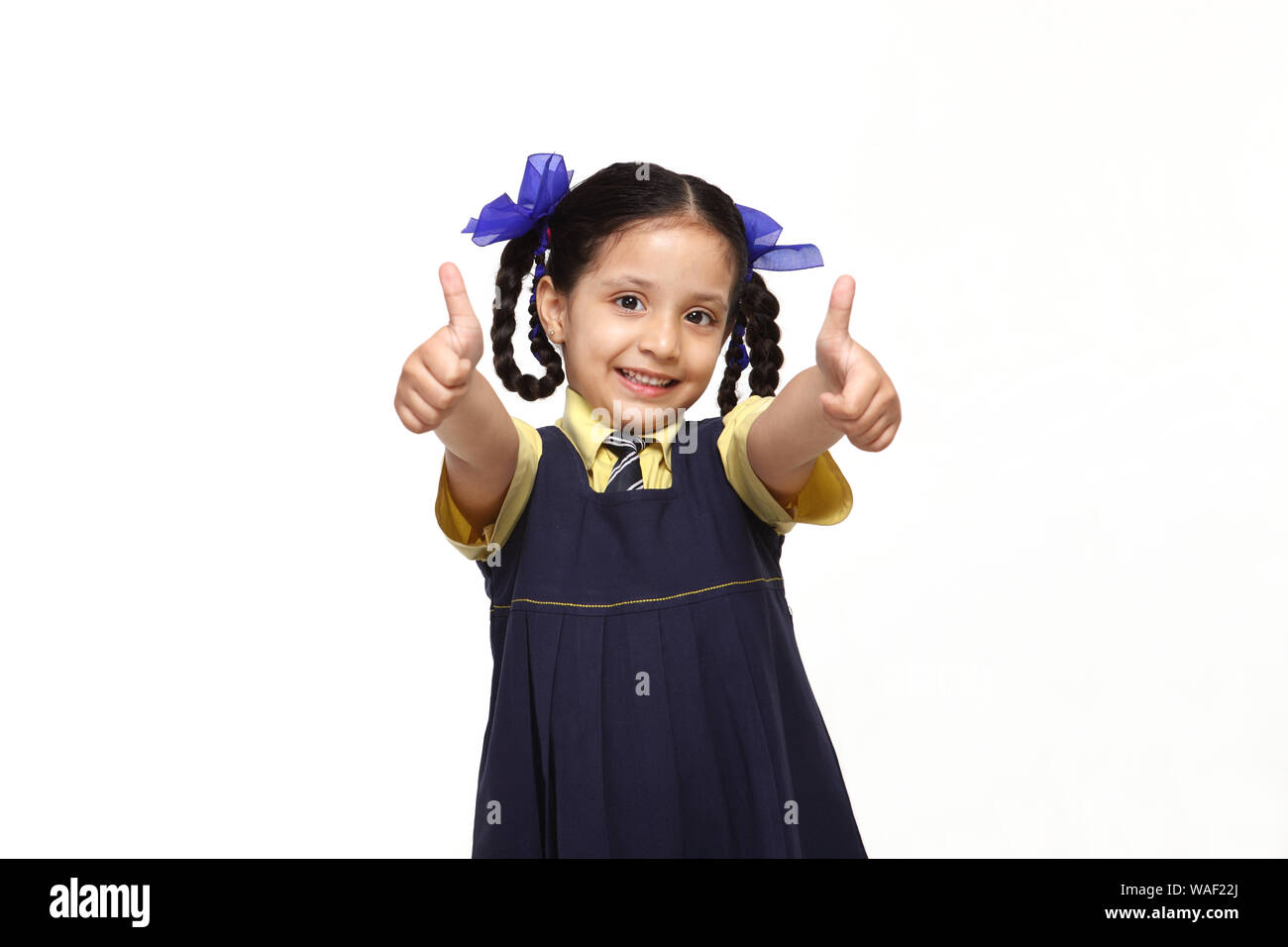Schoolgirl standing and showing thumbs up sign Stock Photo - Alamy