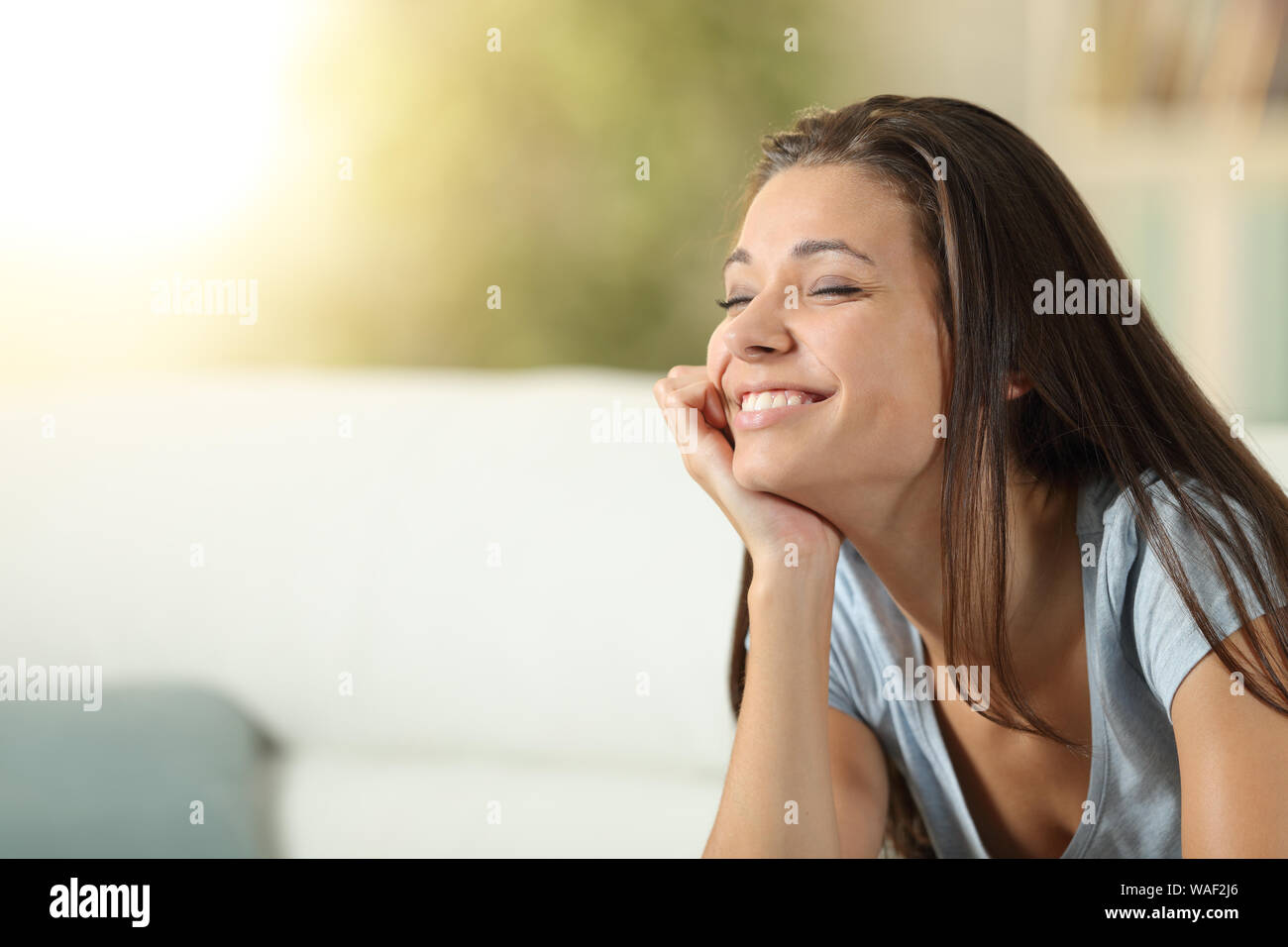 Happy girl meditating at home with closed eyes sitting on a couch Stock Photo
