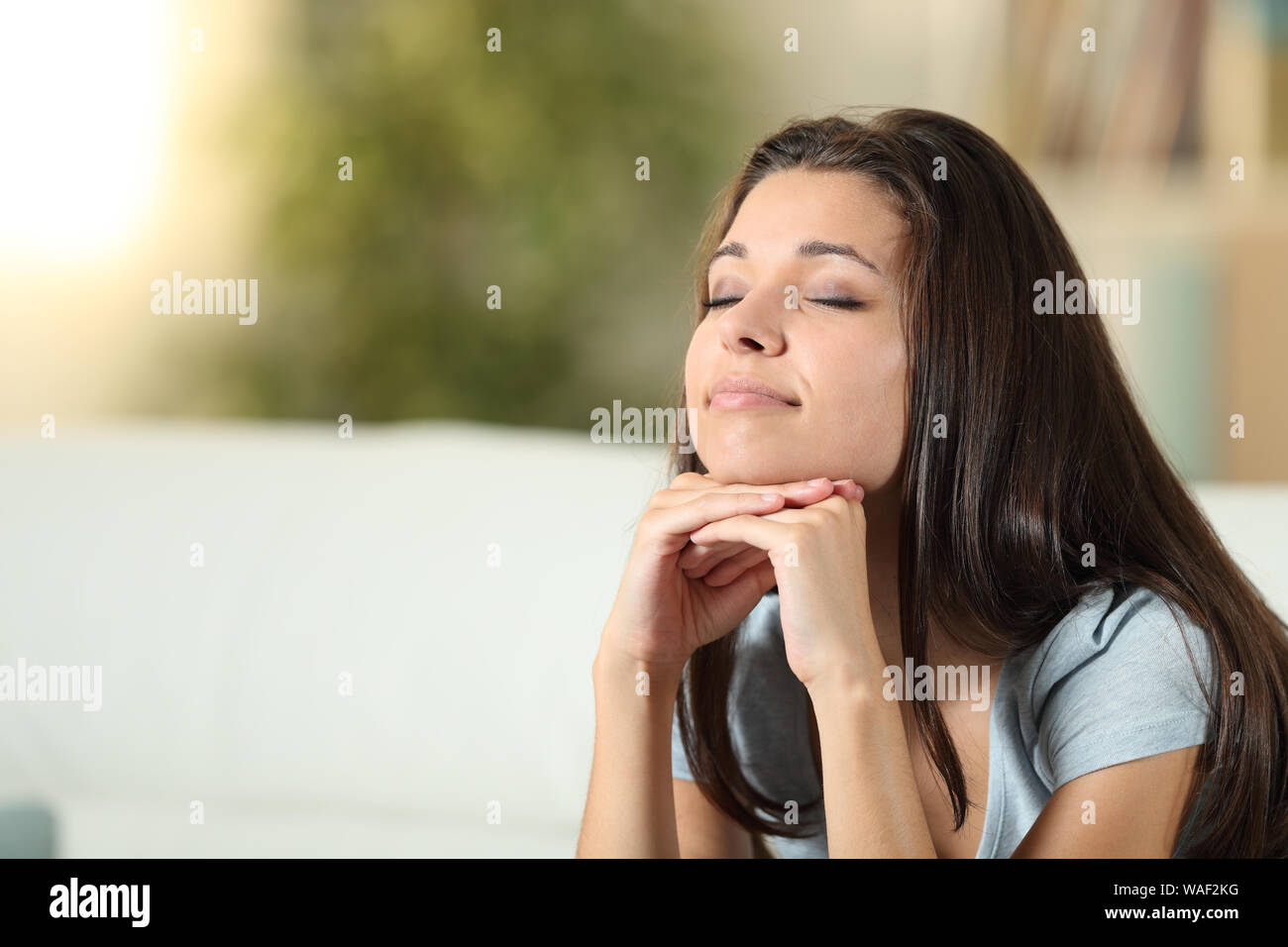 Relaxed woman meditating closing eyes sitting on a couch at home Stock Photo