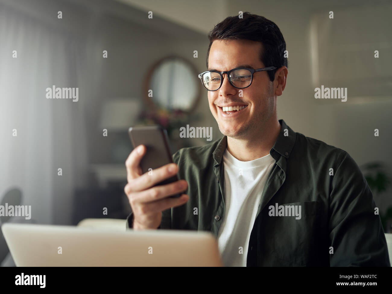 Man smiling while texting messages on mobile phone Stock Photo
