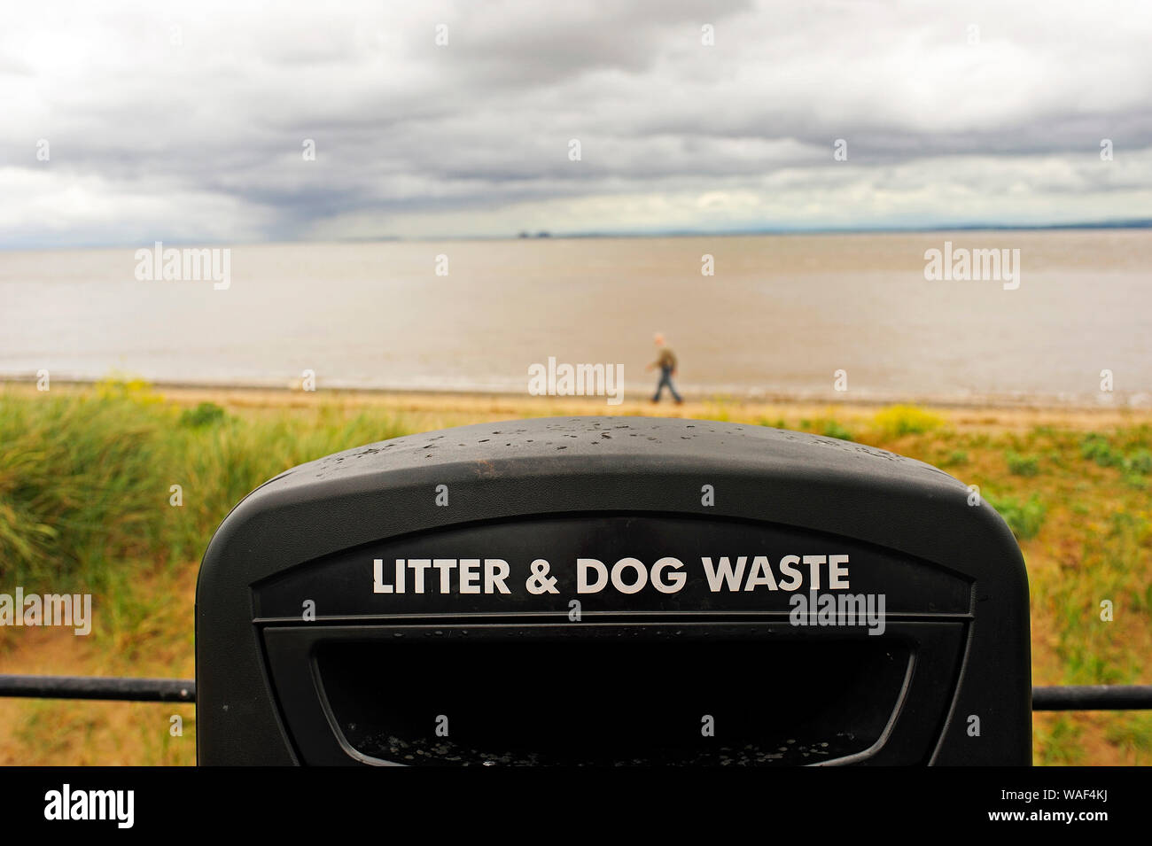 Black plastic rubbish bin for litter and dog waste on Fleetwood seafront on a cold wet day Stock Photo