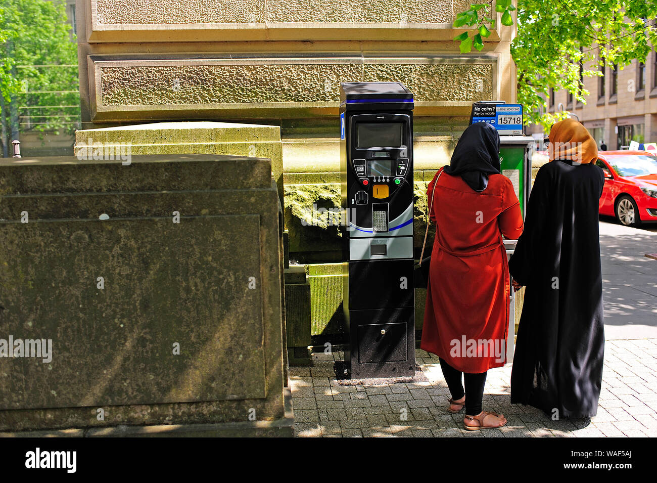 Two Asian women  in traditional dress paying for car parking in Bolton town centre,Greater Manchester,UK Stock Photo