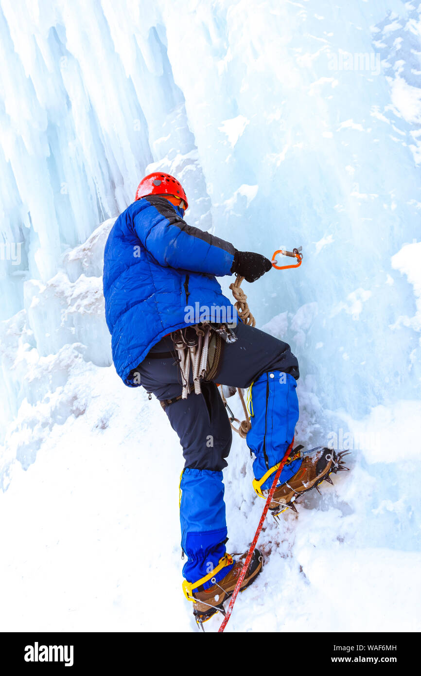 ice climber checks the reliability of the anchor with ice screw before ...