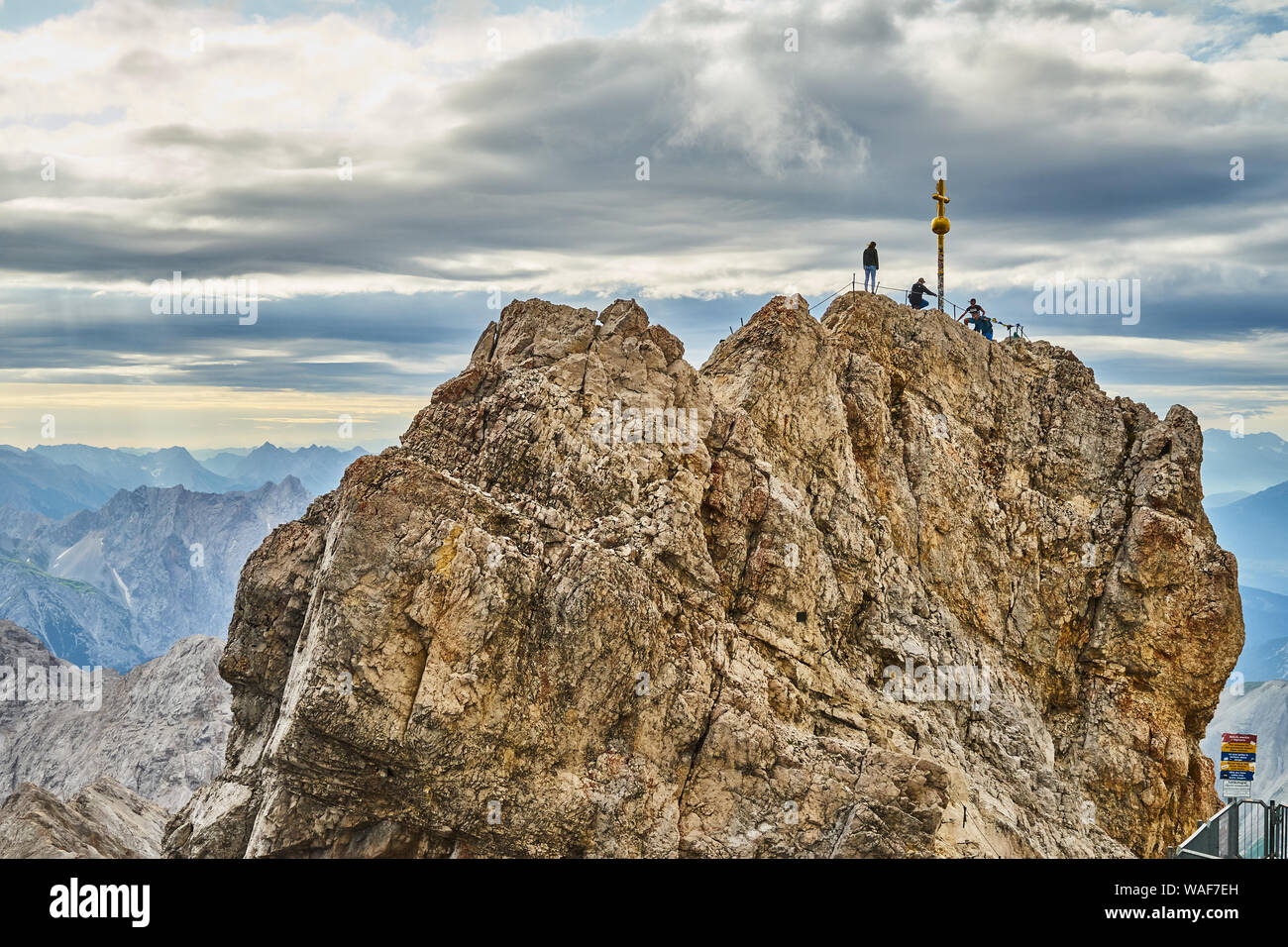 Garmisch-Partenkirchen, Germany, August 5., 2019: Mountaineer next to the summit cross on the summit of Zugspitze, the highest mountain in Germany Stock Photo