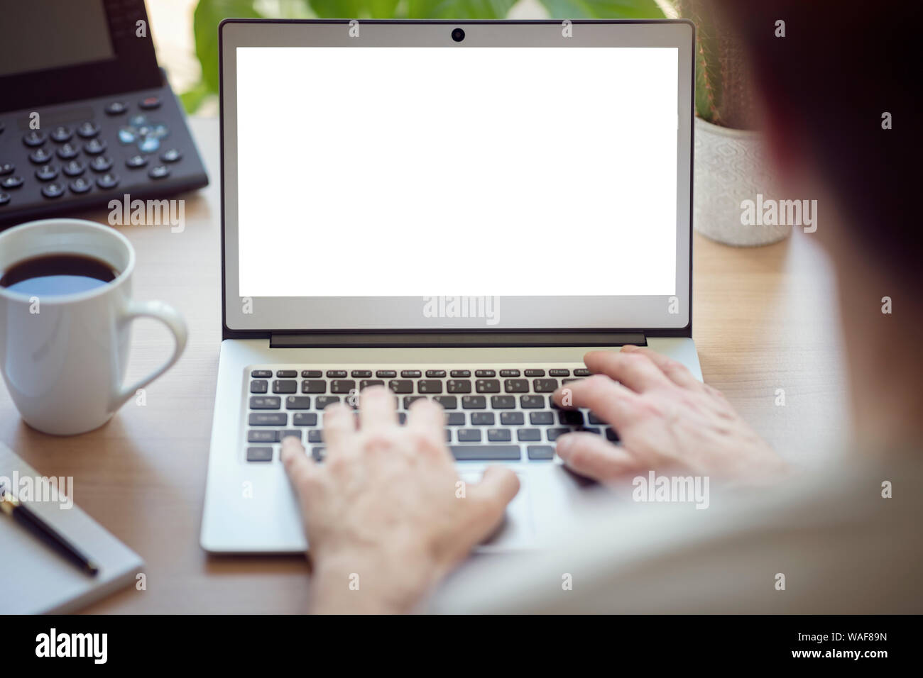 Man with laptop computer on desk working in office with blank screen Stock Photo