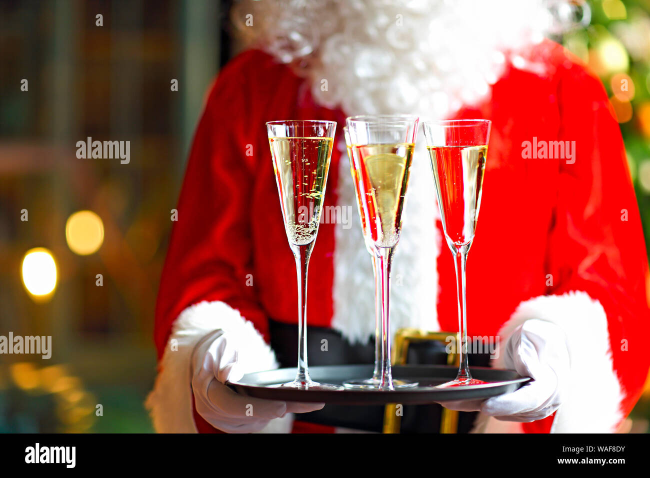 Santa Claus holding champagne glasses on the tray. Closeup Stock Photo