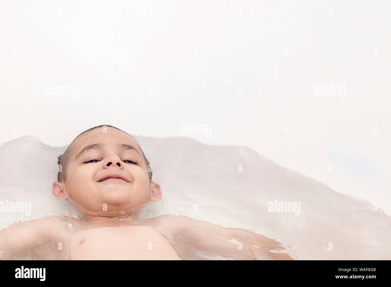 Boy takes a bath. 5-6 years kid having water fun in bathroom. Copy space Stock Photo