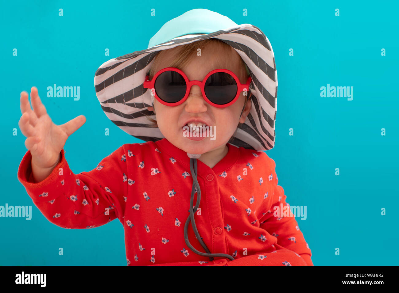 Stylish playful kid in sunglasses and striped hat Stock Photo