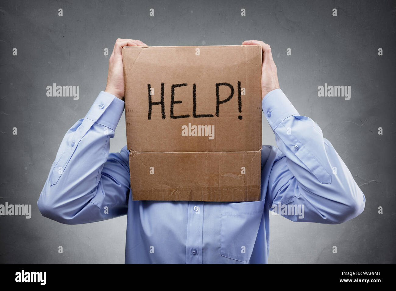 Cardboard box on businessman head asks for help concept for problems, support, overworked or stress Stock Photo