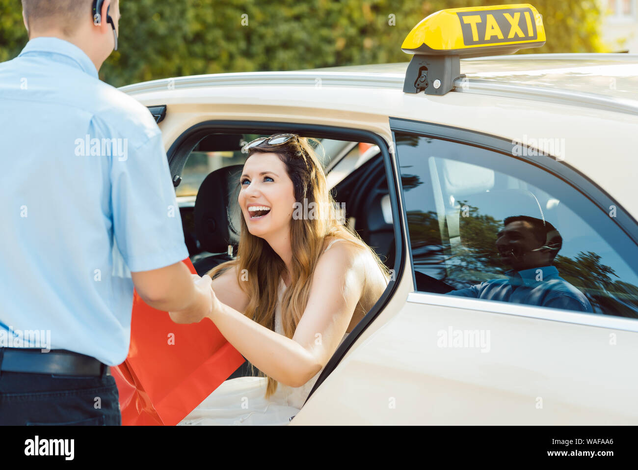 Woman getting out of taxi and the driver helping her Stock Photo