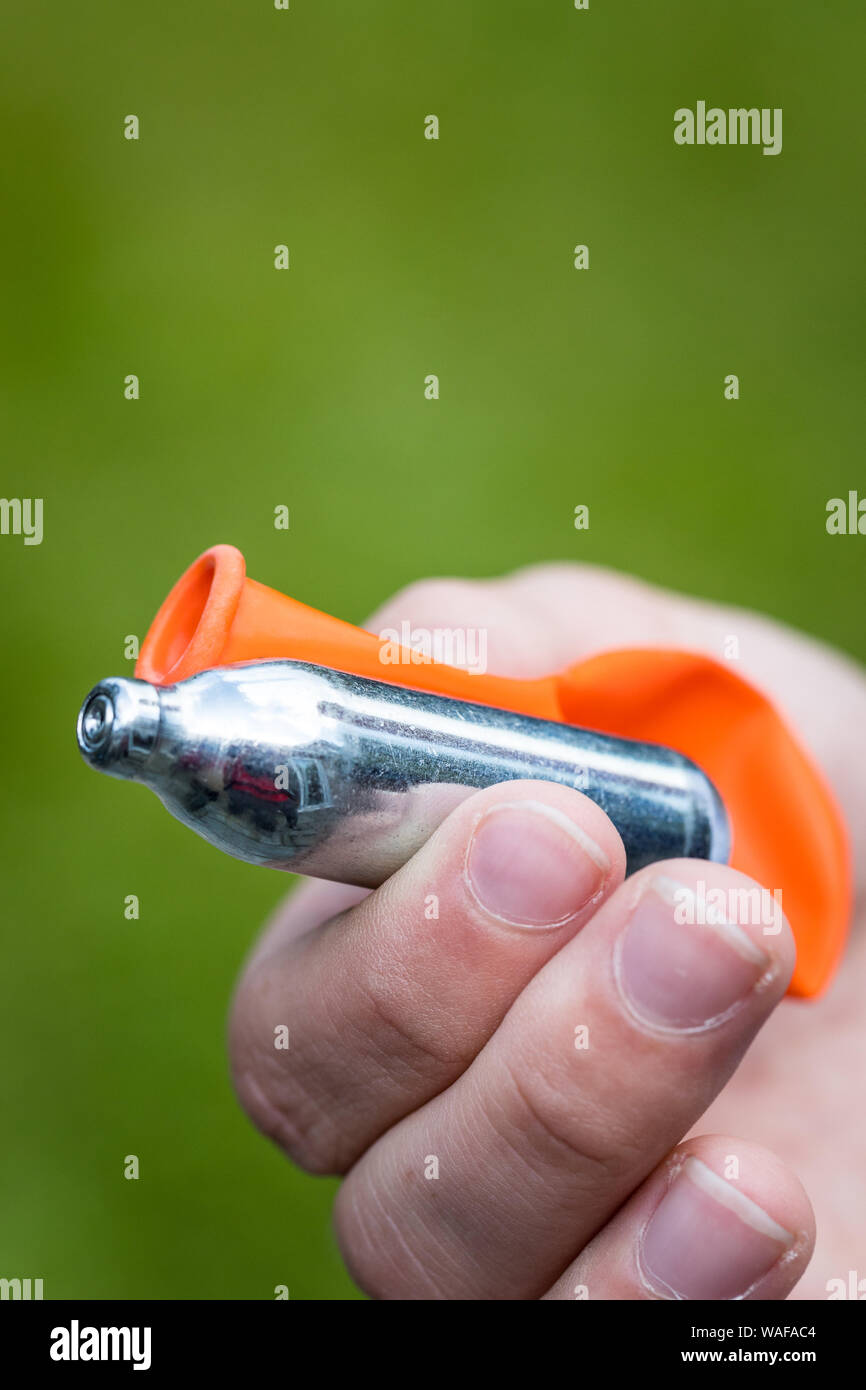 A teenager fills a balloon with nitrous oxide (laughing gas) also known as hippy crack Stock Photo