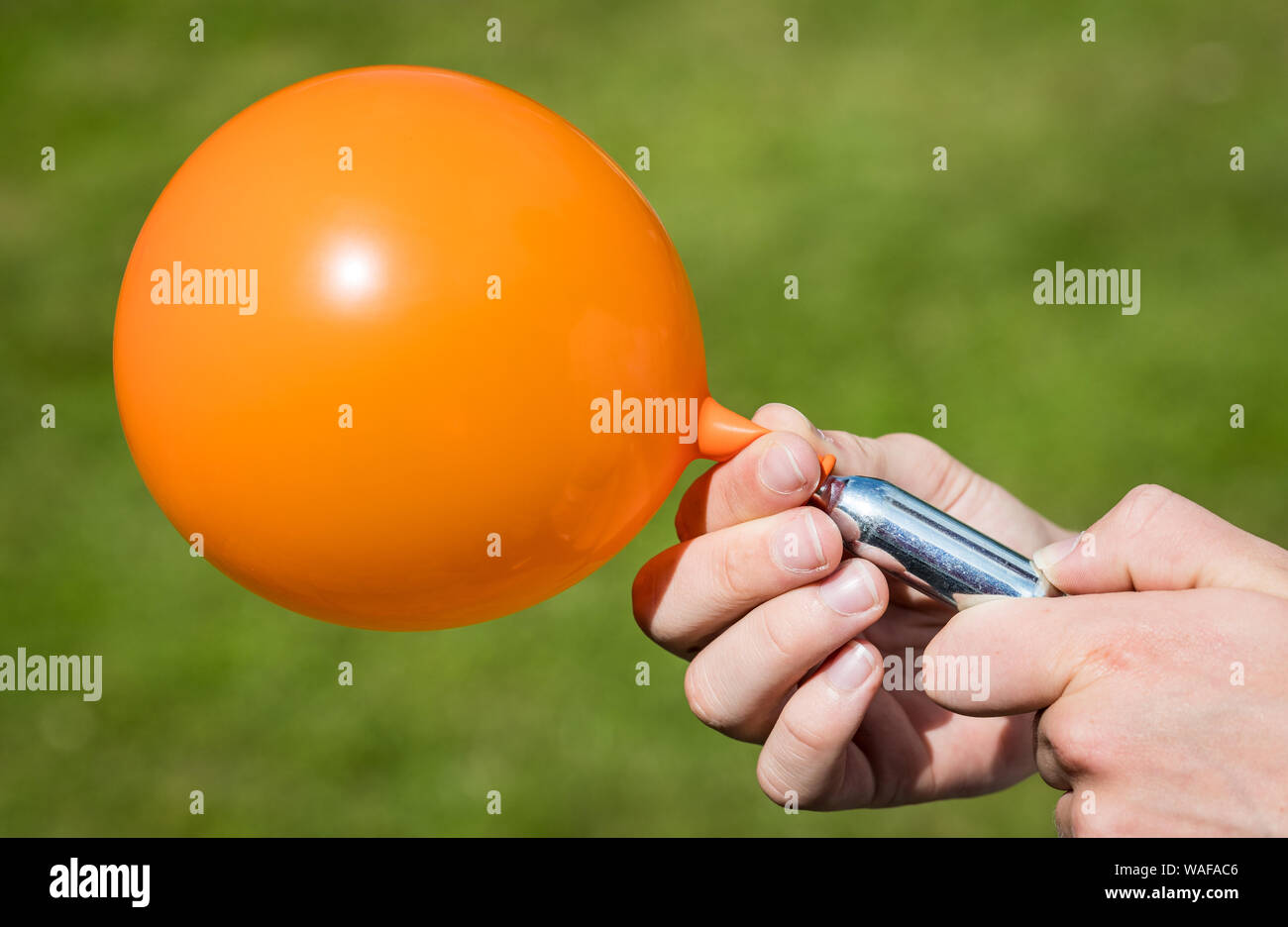 A teenager fills a balloon with nitrous oxide (laughing gas) also known as hippy crack Stock Photo