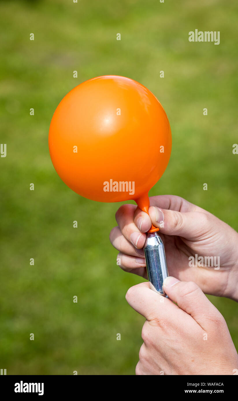 A teenager fills a balloon with nitrous oxide (laughing gas) also known as hippy crack Stock Photo