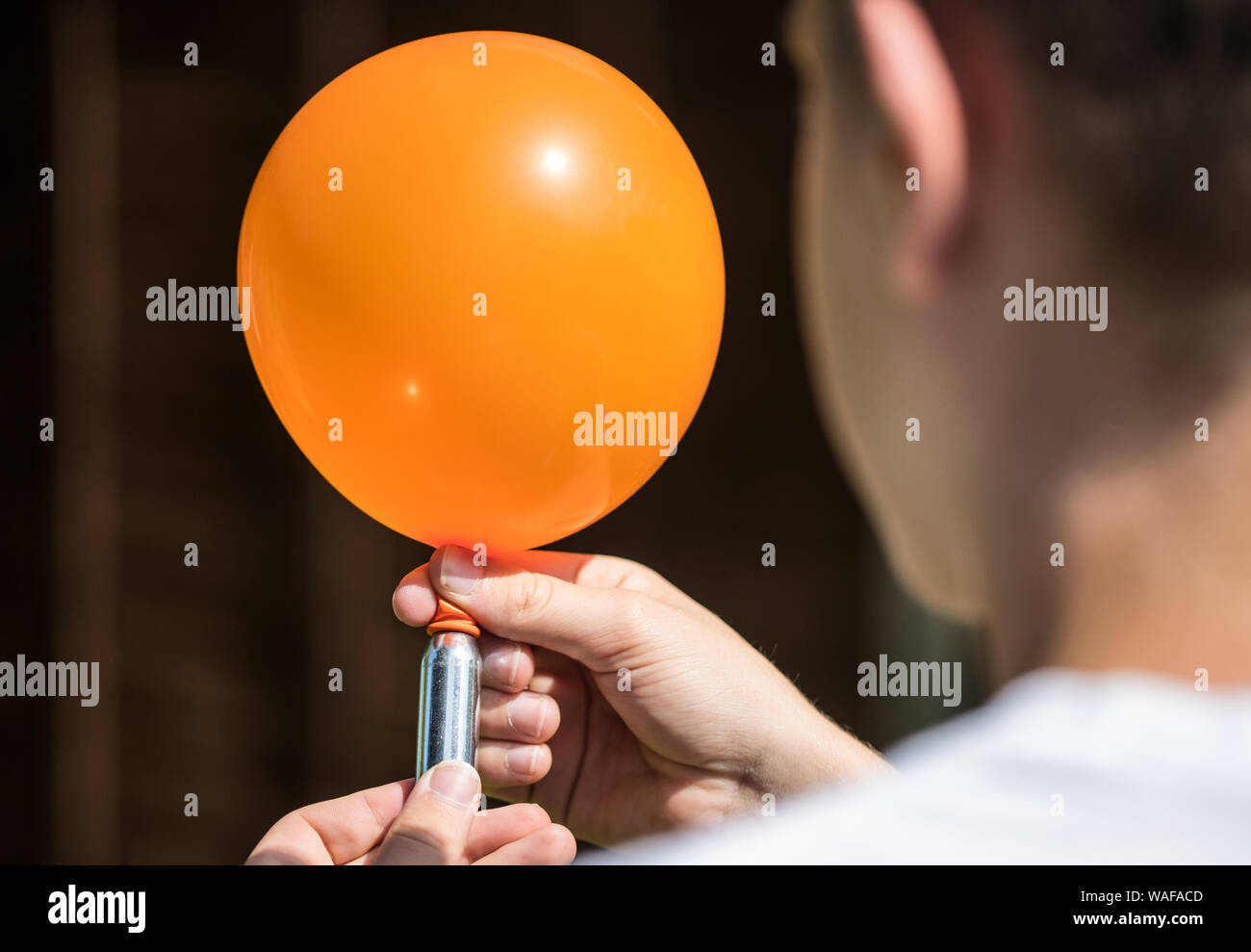 A teenager fills a balloon with nitrous oxide (laughing gas) also known as hippy crack Stock Photo