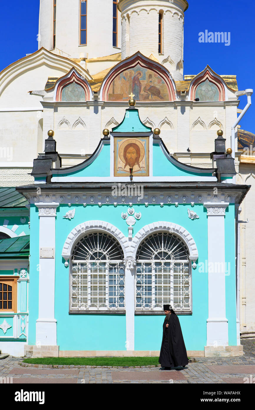 Russian Eastern Orthodox walking past the rear entrance of the Trinity Cathedral at the Trinity Lavra of St. Sergius in Sergiyev Posad, Russia Stock Photo