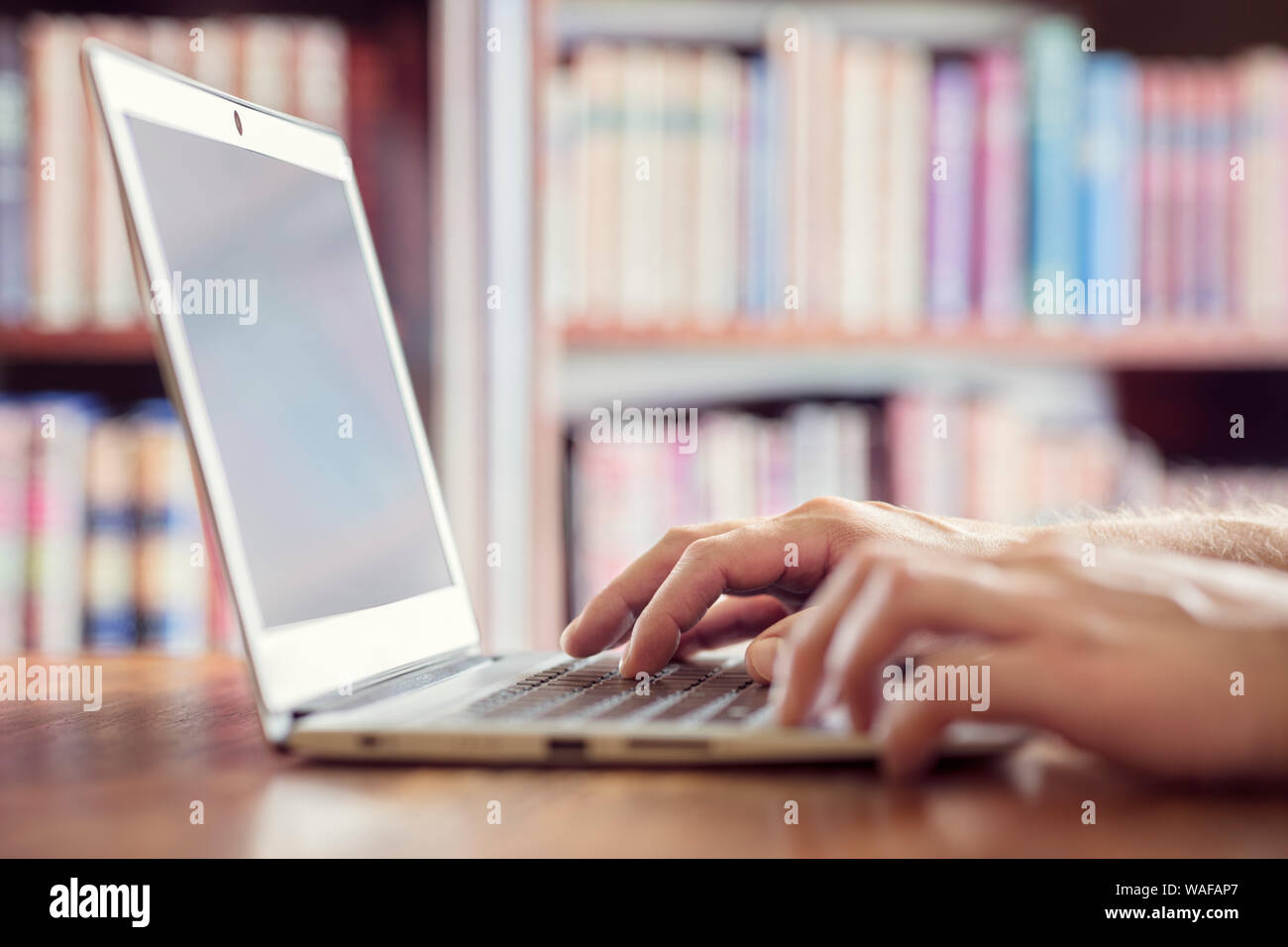 Hands typing on laptop computer in library concept for education, writer or research Stock Photo