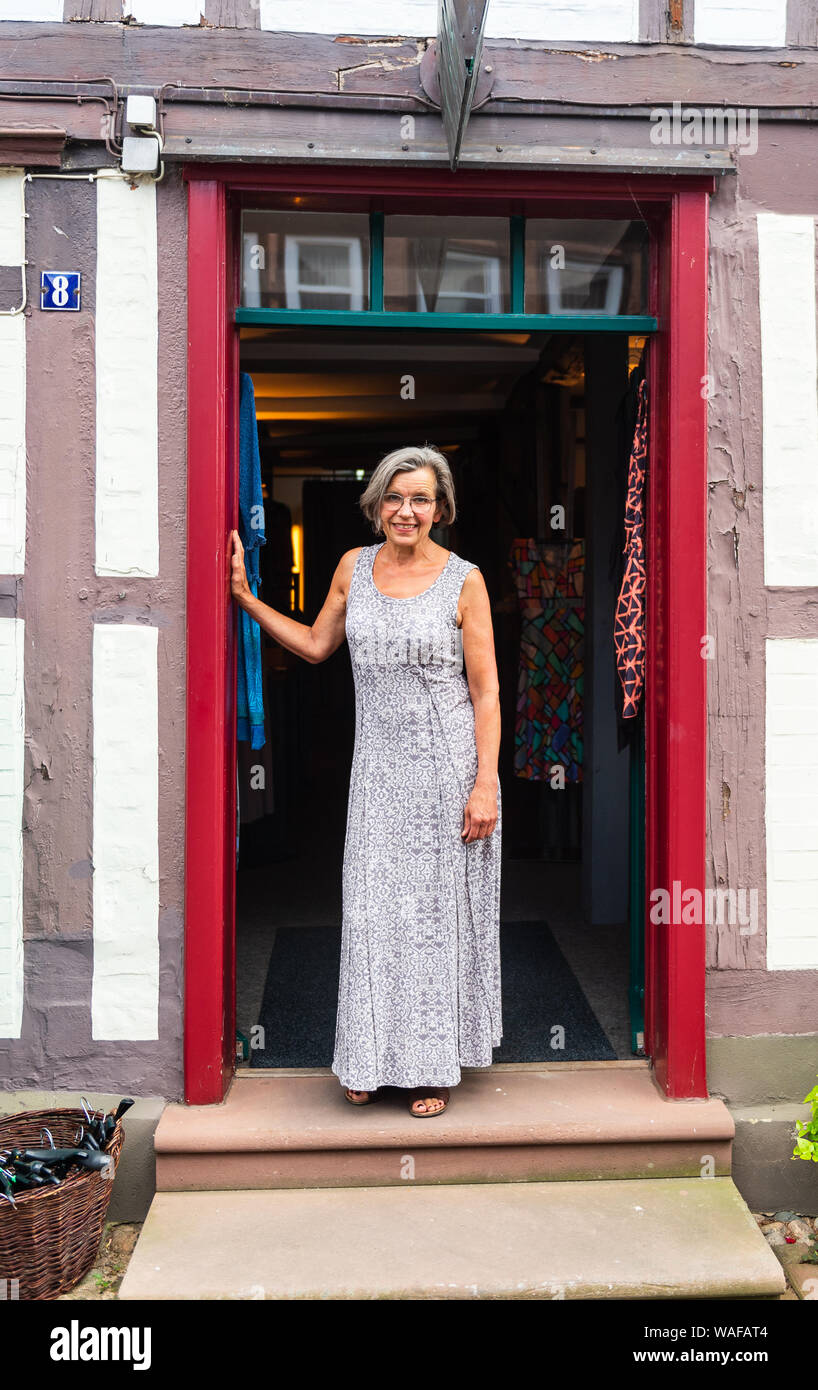 Hitzacker, Germany. 01st July, 2019. Birgit Holsten in front of her shop and is one of the so-called Iselkaufkaufrauen in the old town of Hitzacker. The old town of Hitzacker lies on the Elbe, framed by two arms of the little Jeetzel. But the seemingly idyllic location has not only repeatedly endangered the area known as the city island. The old town was hit by floods several times, the last time it was flooded was in 2006. Credit: Philipp Schulze/dpa/Alamy Live News Stock Photo