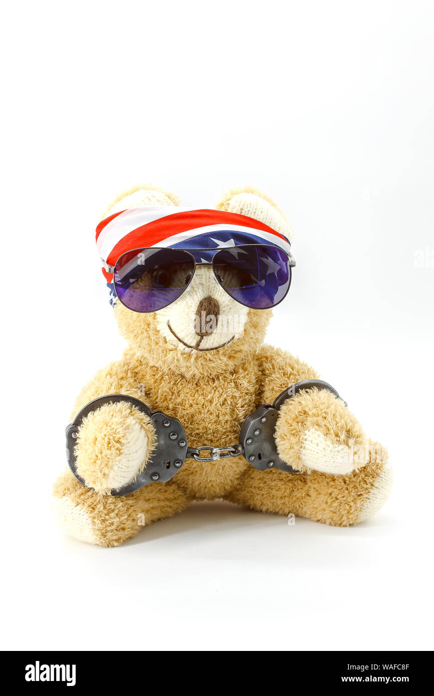 Plush teddy bear with handcuffs on white background Stock Photo