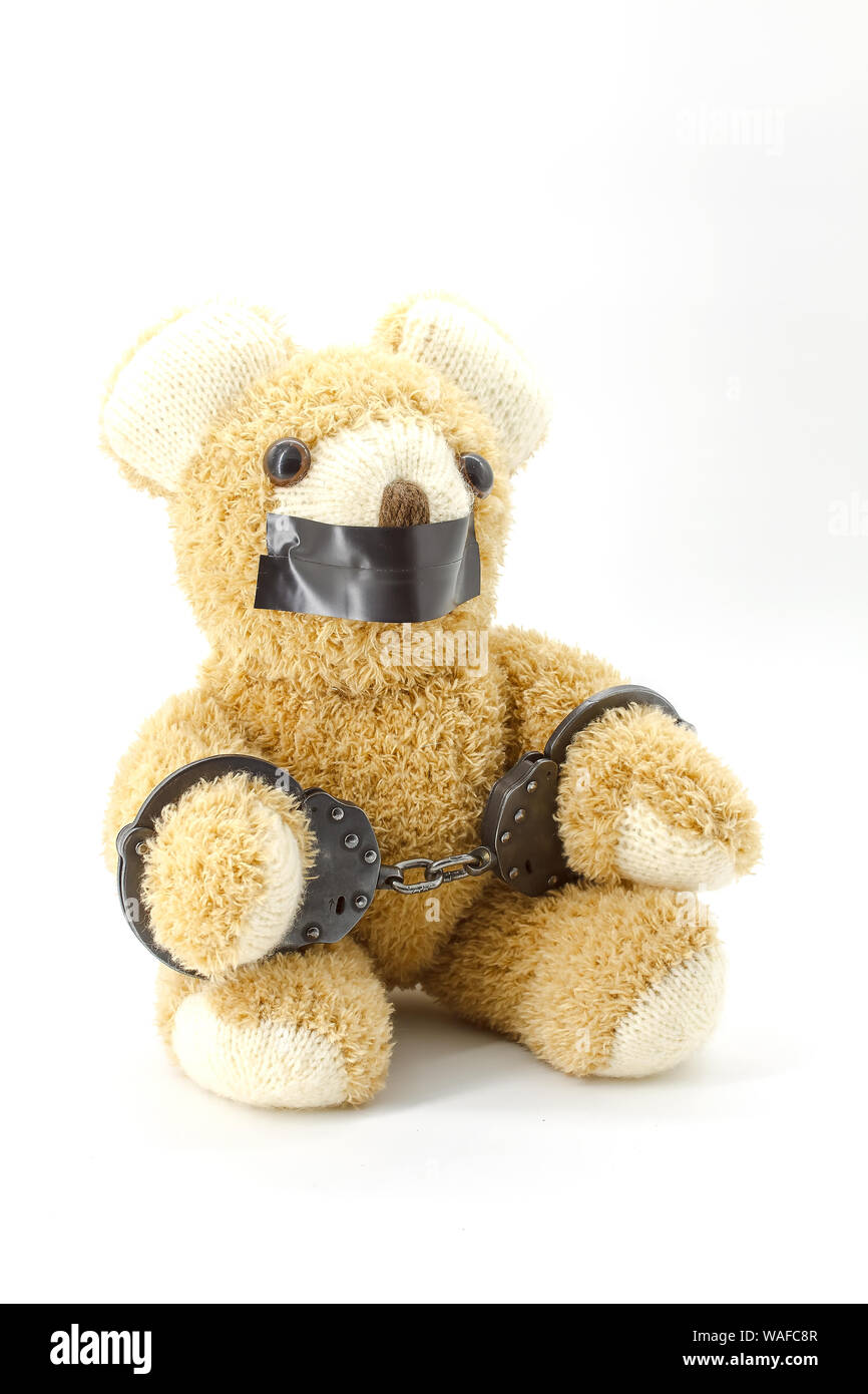Plush teddy bear with handcuffs on white background Stock Photo